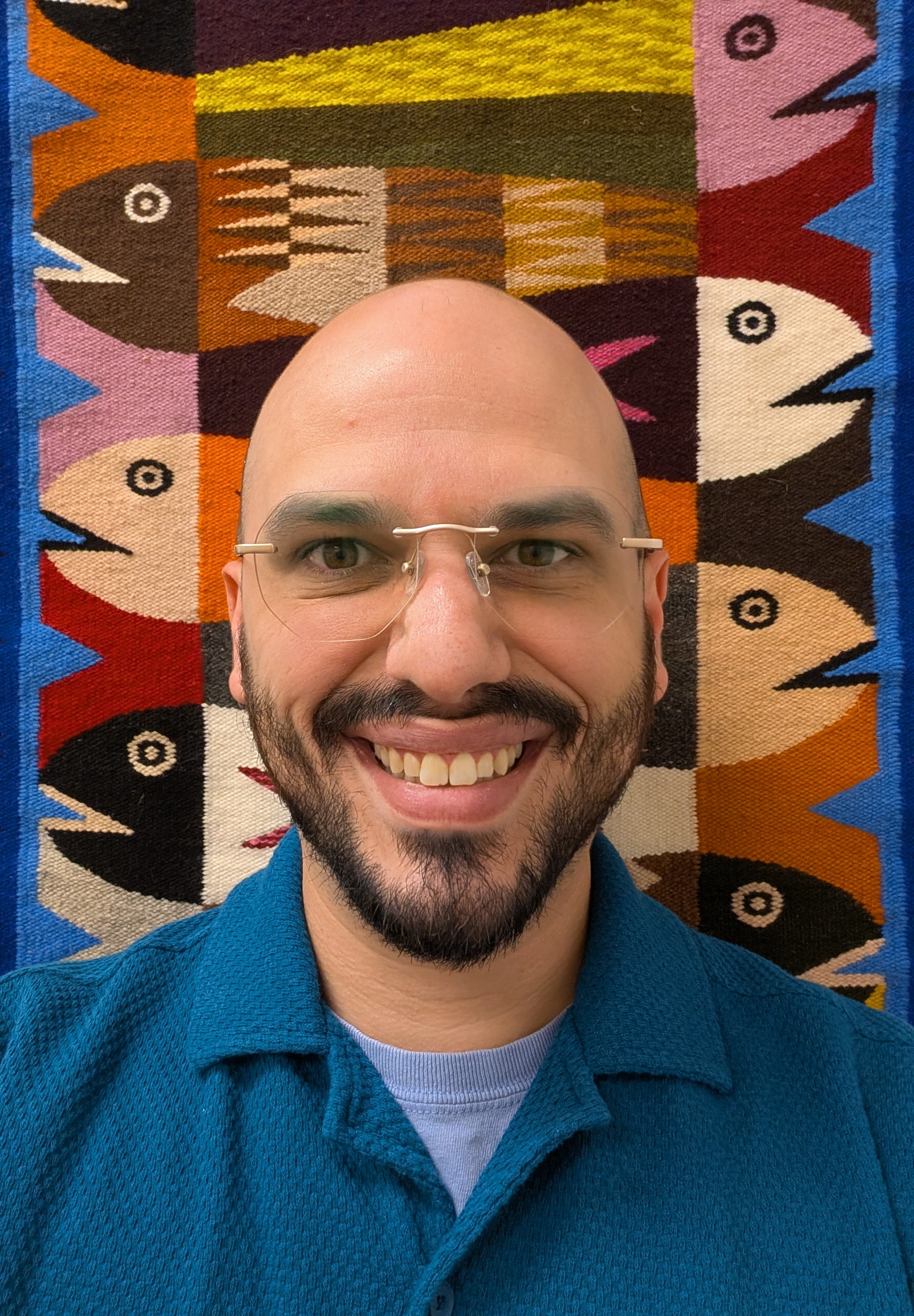 Devin, resident medium at Lodestar, smiling in front of a woven textile